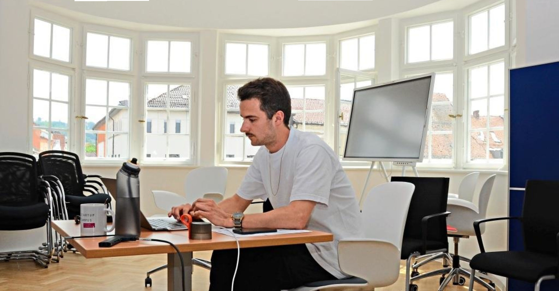 Das Laptop-Ladekabel hängt an einer Kabeltrommel und es fehlt noch an Tischen und Schränken. Dennoch genießt Maximilian Hau von „Career Captain“ seinen (vorläufigen) Arbeitsplatz in einem Besprechungszimmer im zweiten Stock des Schötz-Hauses. Geht man ans Erkerfenster, öffnet sich der Blick auf den Luitpoldplatz mit dem Wochenmarkt, aufs Alte Rathaus und die Grabkirche. −Foto: Katrin Schreiber Das Laptop-Ladekabel hängt an einer Kabeltrommel und es fehlt noch an Tischen und Schränken. Dennoch genießt Maximilian Hau von „Career Captain“ seinen (vorläufigen) Arbeitsplatz in einem Besprechungszimmer im zweiten Stock des Schötz-Hauses. Geht man ans Erkerfenster, öffnet sich der Blick auf den Luitpoldplatz mit dem Wochenmarkt, aufs Alte Rathaus und die Grabkirche. −Foto: Katrin Schreiber